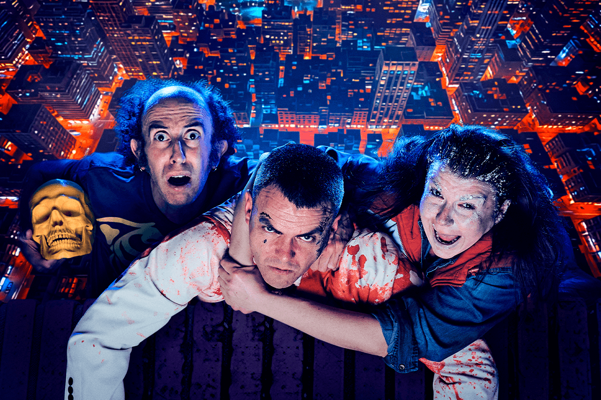 Foto promocional de l’obra Big Fake. Tres intèrprets, dos hòmens i una dona, s’agafen a la vora d’un edifici per no caure al buit replet de gratacels i edificis. Les seves expressions són exaltades, El de l'esquerra sosté una calavera daurada mentre mira amb els ulls molt oberts i la boca oberta a càmera; l’home del centre mira determinat a càmera amb roba tacada de sang, i la de la dreta crida amb el rostre cobert de pols blanca.